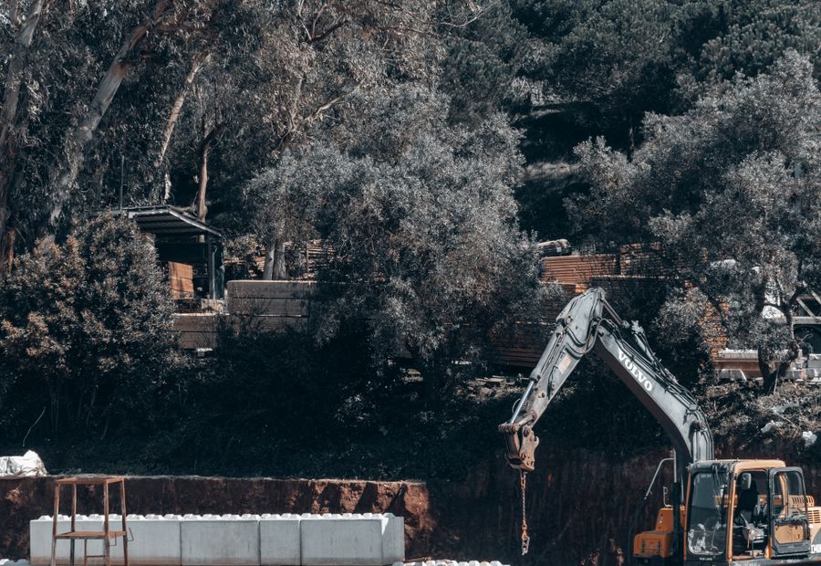 Excavator standing in a large open cut for a commercial septic field
